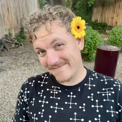 Mike Elliott, smiling, with a yellow flower in his hair